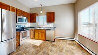Located at 551 Victory Ave S in Sartell, MN, this single-floor, two-bedroom, one-bathroom home offers a comfortable and functional layout. The kitchen is a standout feature, showcasing warm wood cabinetry, dark countertops, and a full suite of stainless steel appliances including a refrigerator, electric range, built-in microwave, and dishwasher. Stone-look tile flooring runs throughout the kitchen, adding durability and style. Natural light filters in through a window above the sink, brightening the space. The open living area is generously sized, with soft carpeting and large windows that allow plenty of natural light to fill the room. Baseboard heating is present throughout. Both bedrooms are well-proportioned, featuring plush carpeting, neutral warm-toned walls, and windows that bring in natural light. Each bedroom benefits from dedicated closet space, providing ample storage. The full bathroom includes a single-sink vanity with wood cabinetry, a wide mirror, and a tub/shower combination, all set atop stone-look tile flooring. A hallway connects the main living areas to the bedrooms, offering a clean and organized flow throughout the home. The overall aesthetic is neutral and move-in ready.