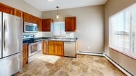 Located at 551 Victory Ave S in Sartell, MN, this single-floor, two-bedroom, one-bathroom home offers a comfortable and functional layout. The kitchen is a standout feature, showcasing warm wood cabinetry, dark countertops, and a full suite of stainless steel appliances including a refrigerator, electric range, built-in microwave, and dishwasher. Stone-look tile flooring runs throughout the kitchen, adding durability and style. Natural light filters in through a window above the sink, brightening the space. The open living area is generously sized, with soft carpeting and large windows that allow plenty of natural light to fill the room. Baseboard heating is present throughout. Both bedrooms are well-proportioned, featuring plush carpeting, neutral warm-toned walls, and windows that bring in natural light. Each bedroom benefits from dedicated closet space, providing ample storage. The full bathroom includes a single-sink vanity with wood cabinetry, a wide mirror, and a tub/shower combination, all set atop stone-look tile flooring. A hallway connects the main living areas to the bedrooms, offering a clean and organized flow throughout the home. The overall aesthetic is neutral and move-in ready.