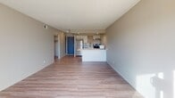 This single-floor unit offers a clean, contemporary design centered around an open-concept living and kitchen area. Light-toned luxury vinyl plank flooring flows throughout the main living spaces, complementing the neutral, light gray wall tones and creating a cohesive, modern aesthetic.

The kitchen is efficiently designed and features white cabinetry with matte black hardware, a quartz-style countertop, subway tile backsplash, and a full suite of stainless steel appliances including a refrigerator, gas range, dishwasher, and range hood. A peninsula counter provides additional workspace and separates the kitchen from the open living area. The living room is generously sized and filled with natural light from a large sliding glass door that opens to a private balcony, offering outdoor views.

The bedroom is carpeted for comfort and includes a ceiling fan with lighting, a window providing natural light, and access to a closet. The bathroom features full-height ceramic tile surrounds in a neutral gray tone enclosing a bathtub and shower combination with brushed nickel fixtures, paired with a standard vanity and toilet. Textured ceilings are present throughout, adding a traditional touch to the otherwise updated interior.