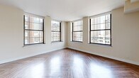 Located in the heart of downtown Detroit on Griswold Street, this 2-bedroom, 1-bathroom residence offers a well-designed layout with a host of refined finishes throughout. Herringbone-patterned hardwood flooring runs seamlessly across the entire unit, lending a timeless and elegant character to each room.

The living area is generously proportioned, wrapped by large, dark-framed industrial-style windows that flood the space with natural light and frame striking views of Detroit's iconic skyline and surrounding historic architecture. The primary bedroom is notably spacious, also benefiting from multiple oversized windows with downtown views, while the second bedroom offers its own window with city-facing exposure.

The kitchen is a functional and stylish centerpiece, featuring white shaker cabinetry, dark countertops, a full suite of stainless steel appliances including a refrigerator, range, and microwave, and a freestanding stainless steel island with pendant lighting above—adding an industrial-chic aesthetic. Open shelving accents the kitchen walls for added utility and style.

The bathroom is clean and contemporary, finished with white subway tile and a glass-enclosed walk-in shower with a built-in corner shelf. Throughout, the warm neutral palette and abundant natural light create a bright, welcoming ambiance well-suited to urban living.