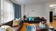 Located at 6301 Overbrook Avenue in Philadelphia, PA, this 2-bedroom, 2-bathroom unit offers a practical and comfortable single-floor layout. Warm hardwood flooring flows through the living room, hallway, and kitchen, lending a cohesive feel throughout the space.

The living room is a welcoming area highlighted by large windows dressed with floor-to-ceiling curtains that allow natural light to fill the room. The kitchen features white cabinetry with open shelving, dark countertops, stainless steel appliances including a dishwasher and refrigerator, and a rear entry door with windows that bring in additional natural light.

A central hallway connects the main rooms, providing a clean and organized flow throughout the unit. The primary bedroom is a well-proportioned room with carpeted flooring, natural light from double windows, a closet, and direct access to a full bathroom. The second bedroom also features carpeted floors and access to the hallway. Both bathrooms are finished with tile flooring — one featuring a pedestal sink and shower-tub combination, and the other a walk-in shower — each presented in a clean, neutral palette. This unit offers a functional and comfortable living arrangement in a residential Philadelphia neighborhood.
