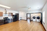 Located at 715 N 16th St in Baton Rouge, Louisiana, this single-floor, one-bedroom, one-bathroom residence offers a thoughtfully designed layout with a clean, modern aesthetic. Warm hardwood-style flooring runs throughout the entire unit, complemented by crisp white walls and bold dark door and trim accents that add visual contrast and definition to each space.

The open living area is bright and airy, featuring a ceiling fan and natural light from windows fitted with blinds. An in-unit laundry area with a full-size washer and dryer is conveniently integrated into the main living space. The well-equipped kitchen includes granite countertops, dark lower cabinetry paired with warm wood upper cabinets and open shelving, a double-basin sink, a black gas range with a stainless steel ventilation hood, a dishwasher, and a full-size refrigerator.

The bedroom offers a comfortable, spacious feel with dual windows that invite natural light, a ceiling fan, a closet with built-in hanging rods, and an electrical panel neatly recessed into the wall. The bathroom is designed with accessibility in mind, featuring stainless steel grab bars, hardwood-style flooring, and an over-toilet storage cabinet, providing both functionality and ease of use throughout.