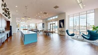 Located at 1 Harbor Point Rd in Stamford, Connecticut, this generously sized single-floor amenity space offers a sophisticated and versatile environment designed for both leisure and productivity. The open-plan layout is anchored by soaring ceilings and floor-to-ceiling windows that flood the interiors with natural light and frame sweeping views of the harbor and surrounding waterfront landscape.

The main gathering area features a striking turquoise island counter with pendant lighting, complemented by multiple seating arrangements including contemporary lounge chairs in bold teal tones. A dedicated dining area provides communal tables ideal for casual meals or group gatherings. The game room is equipped with a billiards table, ping-pong table, and a wall-mounted television, set against nautical-inspired artwork and patterned area rugs.

A co-working zone offers professional workstations alongside comfortable lounge seating, while two conference rooms — finished in calming coastal blue tones with patterned carpeting, large conference tables, and mounted displays — serve as polished meeting environments. Throughout the space, warm hardwood-style flooring, curated artwork, and lush tropical plants reinforce an upscale, coastal-modern aesthetic. Direct access to an outdoor terrace further enhances the connection to the vibrant Harbor Point waterfront setting.