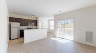 This single-floor residence offers a well-designed, open-concept layout that seamlessly connects the kitchen and living area. The kitchen is outfitted with rich, dark espresso cabinetry, granite countertops, and a full suite of stainless steel appliances including a refrigerator, electric range, and over-the-range microwave. A peninsula counter provides additional prep space and serves as a natural divider between the kitchen and the living area. Track lighting overhead enhances functionality in the kitchen, while a pendant light adds a subtle decorative touch near the dining space.

The living area is bathed in natural light, courtesy of large sliding glass doors that open onto a private balcony, offering outdoor views and a seamless indoor-outdoor connection. Light wood-look flooring runs throughout the main living spaces, lending a clean, contemporary feel to the home.

The bedrooms feature plush wall-to-wall carpeting and multiple windows dressed with blinds, ensuring ample natural light and privacy. Two full bathrooms are finished with large-format tile flooring and dark vanity cabinetry with light countertops. One bathroom includes a soaking tub with built-in shelving, while both feature grab bars and clean, neutral finishes throughout. The overall aesthetic is fresh, functional, and move-in ready.