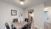 This single-floor residence at 2301 W Lexington Ave in Elkhart, Indiana, offers a thoughtfully designed layout with a cohesive blend of modern finishes and functional living spaces throughout. The living room provides a comfortable, open setting with wood-look flooring, neutral walls, and ample room for seating arrangements, creating a welcoming atmosphere for relaxing or entertaining. Adjacent to the living area, the dining space accommodates a full dining table and connects seamlessly to the kitchen, which is outfitted with rich dark cabinetry, granite countertops, stainless steel appliances including a refrigerator and range, and a dishwasher. A sliding glass door in a secondary room fills the space with natural light and offers outdoor access. The unit features two bedrooms, each with plush carpeting, neutral tones, and generous closet space. One bedroom benefits from a large window that enhances natural brightness. Both bathrooms are finished with granite-top vanities, rich wood cabinetry, and wood-look tile flooring, delivering a clean and polished aesthetic. Throughout the unit, consistent design choices — including textured ceilings, brushed nickel hardware, and wood-look flooring in main areas — contribute to a unified and comfortable living environment.