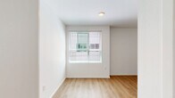This efficiently designed single-floor studio unit offers a thoughtfully organized layout that maximizes every square foot. Throughout the space, light wood-tone laminate flooring and crisp white walls create a clean, bright atmosphere that feels open and welcoming.

The main living area is an open, flexible space bathed in natural light from a large window fitted with horizontal blinds. A built-in closet with a hanging rod provides convenient storage directly within the living area, keeping the floor plan streamlined and functional.

The compact kitchen is neatly appointed with warm wood-toned cabinetry, both upper and lower, offering ample storage. A countertop workspace, a stainless steel mini-refrigerator, and a built-in microwave provide all the essential amenities needed for day-to-day living.

The bathroom is well-appointed and practical, featuring warm wood-finish cabinetry with an integrated vanity and sink, a toilet, and an open walk-in shower with a chrome towel bar. The wood-tone flooring continues seamlessly from the main living area into the bathroom, reinforcing a cohesive, unified aesthetic throughout the unit.

Overall, this studio presents a clean, modern, and highly functional living environment with consistent finishes and smart use of space.