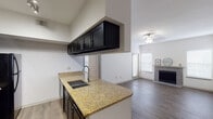 This single-floor, one-bedroom, one-bathroom residence offers a well-designed layout with modern finishes throughout. The kitchen is a standout feature, equipped with dark espresso cabinetry, granite countertops, a tile backsplash, and a full suite of black appliances including a refrigerator, range, and built-in microwave. A peninsula with an undermount sink and overhead cabinetry provides additional workspace and connects the kitchen to the main living area, which flows naturally to the space.

The living room is bright and open, featuring wood-style flooring, multiple windows with natural light, a ceiling fan with light fixture, and a tile-surround fireplace that serves as a focal point. An exterior door provides access to an outdoor area.

The bedroom offers plush carpeting, a ceiling fan, and a clean, well-proportioned layout. The bathroom continues the design theme with dark cabinetry, granite countertops, an undermount sink, a large mirror, and wood-style flooring. The consistent use of granite and dark cabinetry across the kitchen and bathroom gives the space a cohesive, contemporary aesthetic throughout.