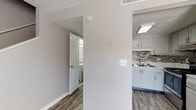 This two-story residence presents a cohesive, updated interior defined by neutral gray tones, wood-look luxury vinyl flooring on the main level, and textured ceilings throughout. The layout is efficiently organized, with living and kitchen areas situated on the lower floor and bedrooms accessible from both levels.

The kitchen is a standout feature, equipped with white shaker-style cabinetry, marble-look countertops, a stainless steel double-basin sink, and a stainless steel electric range. A mosaic tile backsplash in muted tones of gray, brown, and black ties the space together with a contemporary aesthetic.

The living area benefits from a full-length sliding glass door fitted with vertical blinds, allowing for natural light and outdoor access. Adjacent rooms on the main floor include a bathroom featuring a soaking tub with a white tile surround accented by a decorative mosaic border, echoing the kitchen's design language.

The bedrooms are carpeted in neutral gray tones and receive natural light through blinded windows. Each bedroom includes closet access, with textured ceilings maintaining a consistent finish throughout. The overall ambiance is clean, modern, and move-in ready.