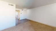 Located in Phoenix, AZ, this single-floor unit features 2 bedrooms, 1 bathroom, and a kitchen within a compact and efficiently designed layout. The living area transitions between wood-look vinyl plank flooring and neutral wall-to-wall carpeting found throughout the bedrooms, providing a warm, consistent feel. The primary bedroom is generously sized, offering ample space for furnishings, and features two closet doors along one wall—ideal for storage. A second bedroom is bright and naturally lit by a window that lets in abundant Arizona sunshine, with soft carpet underfoot and a textured ceiling overhead. The kitchen is equipped with warm wood-toned cabinetry extending to the ceiling for maximum storage, white appliances including a refrigerator, range, and dishwasher, and a double-basin sink. Wood-look plank flooring completes the kitchen's clean, functional aesthetic. The full bathroom includes a white tub and shower combination with chrome fixtures and tile flooring, keeping the space practical and easy to maintain. Throughout the unit, white walls and textured ceilings create a neutral canvas, while ceiling-mounted lighting provides consistent illumination. The straightforward floor plan ensures easy flow between all rooms, making this a well-organized and livable space in the heart of Phoenix.