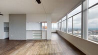 Penthouse B is a two-bedroom, two-bathroom residence in Little Rock, Arkansas, offering an elevated urban living experience with expansive city views and thoughtfully designed interiors. Rich hardwood flooring flows throughout the entire unit, anchoring each room with warmth and continuity.

The open living area is a standout feature, framed by a wall of floor-to-ceiling windows that flood the space with natural light and deliver sweeping panoramic views of the Little Rock skyline. A textured brick accent wall adds architectural character, complemented by a built-in bar area with glass shelving and a ceiling fan overhead.

The kitchen is well-appointed with white shaker cabinetry extending to the ceiling, granite countertops, a classic white subway tile backsplash, and a full suite of stainless steel appliances including a gas range, microwave, dishwasher, and refrigerator.

Both bathrooms are finished with white subway tile surrounds, dark-toned floating vanities with undermount sinks, and wood-look flooring that ties seamlessly to the rest of the unit. The bedrooms are generously sized, each offering built-in closets with shelving and hanging rods for ample storage. Penthouse B combines modern finishes with high-rise living for a distinctive residential experience.