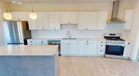 This contemporary 870 square foot single-story residence in Victoria, MN offers a thoughtful layout with two bedrooms and a well-appointed kitchen. The heart of the home is an open-concept living area anchored by a sleek, modern kitchen. White cabinetry extends to the ceiling, complemented by stainless steel appliances and a striking gray island with ample seating. Pendant lighting and recessed fixtures illuminate the space, while large windows invite natural light.

The kitchen flows seamlessly into the living area, ideal for entertaining. Light wood-look flooring unifies the space, creating a warm, inviting atmosphere. The bedrooms feature plush carpeting and spacious closets with ample storage. The primary bedroom, measuring 130 square feet, provides a cozy retreat.

Throughout the home, neutral tones and clean lines create a canvas for personal style. A covered outdoor area, visible through sliding glass doors, extends the living space. This efficiently designed home maximizes its 870 square feet, offering comfortable living in a contemporary package.