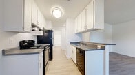 This well-appointed one-bedroom, one-and-a-quarter-bath residence in Carmichael offers a functional and comfortable single-floor layout. Light wood-style flooring runs throughout, creating a cohesive and bright atmosphere across all rooms.

The galley-style kitchen is efficiently designed with white cabinetry lining both walls, offering ample upper and lower storage. Black appliances — including a gas range, refrigerator, and dishwasher — contrast cleanly against the white cabinetry and gray countertops. A flush ceiling light illuminates the space.

The kitchen opens toward the living area, which benefits from a ceiling fan and a window that brings in natural light with views of surrounding greenery. A sliding glass door leads to a private balcony, extending the living space outdoors.

The bedroom is a comfortable size, featuring a window with natural light, light wood-style flooring, and direct access to a dedicated walk-in closet with built-in shelving. An additional window provides further brightness to the room.

The bathroom features a clean, white design with a vanity, mirror cabinet, toilet, and a shower-tub combination. The hallway connecting the rooms adds a sense of separation and privacy. Overall, the unit presents a clean, neutral palette ideal for a range of living styles.