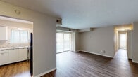 Located at 1748 Jennifer Rd in Lexington, Kentucky, this single-floor unit offers a well-organized layout with a clean, neutral aesthetic throughout. The open living area is finished with durable hardwood-style flooring and features a textured ceiling, a wall-mounted HVAC unit, and a sliding glass door flanked by vertical blinds that opens to a private balcony, filling the space with natural light and outdoor views. An adjacent area provides additional room for flexible use, connected by an open passageway that enhances the sense of flow between spaces. The kitchen is efficiently designed with white cabinetry, granite-look countertops, a stainless steel sink, a window above for natural light, and black appliances including a coil-top range and refrigerator, all set above hardwood-style flooring. The bedrooms are comfortably carpeted and feature neutral-toned walls, natural light from windows with blinds, and ceiling ventilation. The bathroom is outfitted with a tub-shower combination, white tile surround, a window for ventilation, and a vanity with mirror. Throughout the unit, clean white baseboards and a consistent neutral color palette create a cohesive and move-in-ready environment.