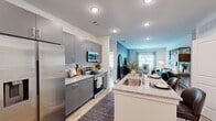 Located at 500 River Knoll Way in Columbus, Georgia, this thoughtfully designed single-story residence offers two bedrooms and three bathrooms within a well-utilized floor plan. The open-concept layout connects the kitchen and living areas seamlessly, creating a bright and functional living environment.

The kitchen is a standout feature, equipped with sleek gray cabinetry, granite-style countertops, stainless steel appliances, and a central island with bar seating that doubles as a dining space. Recessed lighting and light wood-tone flooring run throughout, contributing to a clean, contemporary aesthetic.

The living room benefits from natural light through large windows with outdoor views, while a bold blue accent wall adds character to the primary bedroom. That bedroom includes a walk-in closet with wire shelving systems for organized storage. The second bedroom is equally well-appointed with natural light and ample closet space.

Each of the three bathrooms features gray vanities with granite-style countertops and tiled tub-shower combinations. A dedicated in-unit laundry closet houses a full-size washer and dryer. The overall ambiance is modern and cohesive, with consistent finishes throughout.