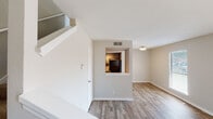 This two-story, 1-bedroom townhome in Tulsa, Oklahoma offers a practical and well-organized layout spread across two distinct levels. The main level features an open living area finished with wood-style luxury vinyl plank flooring, neutral-toned walls, and a sliding glass door that allows natural light to fill the space while providing access to the outdoors. A staircase leads to the upper level, adding a sense of architectural depth to the interior. The kitchen is thoughtfully designed with a pass-through window opening to the living area, dark cabinetry, light countertops, a double-basin stainless steel sink, a dishwasher, and track lighting overhead. The upper level hosts the bedroom, which is carpeted for comfort and features a ceiling fan with multiple windows that bring in natural light. The bedroom connects directly to a private bathroom and includes an additional closet for storage. A linen or utility access panel is also present on the upper level. Throughout the townhome, consistent neutral finishes, clean white trim, and modern fixtures contribute to a cohesive and move-in-ready aesthetic. The two-floor layout provides a clear separation between living and sleeping areas, making this townhome a functional and comfortable residence in Tulsa.