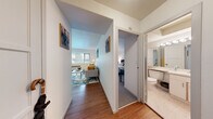 Located at 1000 SW Vista Ave in Portland's vibrant SW Hills neighborhood, this single-floor residence offers a thoughtfully organized layout designed for comfortable everyday living. A welcoming entry hallway with warm hardwood flooring connects the main living areas and provides immediate access to the bathroom, creating an efficient and intuitive flow throughout the unit.

The living room is a bright, inviting space anchored by a wide, multi-pane window fitted with blinds that frame views of the surrounding urban greenery. Hardwood floors continue throughout, complementing the clean white walls and providing a warm, cohesive aesthetic.

The galley-style kitchen is efficiently designed with white cabinetry lining both sides, offering ample storage and counter space. It features an electric range with overhead ventilation, a full-size refrigerator, dishwasher, and a sink — all laid out to maximize functionality within the streamlined footprint.

The bedroom is a serene retreat with plush carpet flooring, a generous window dressed with decorative curtains, and built-in closet storage. Natural light filters in softly, creating a calm and restful atmosphere.

The bathroom is clean and functional, featuring a vanity with under-sink storage, a large mirror with overhead lighting, a tiled tub-shower combination, and classic mosaic tile flooring.