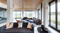 Central Park West is a thoughtfully designed single-floor amenity and leasing space that seamlessly blends modern aesthetics with functional layout. The space is immediately defined by its striking slatted wood ceiling, which runs continuously throughout and lends warmth and architectural interest to the otherwise crisp, white interior.

Upon entry, a curved wood-paneled reception desk greets visitors beneath embedded linear lighting, setting a polished, professional tone. The reception area features large floor-to-ceiling windows that flood the space with natural light and offer open views of the surrounding neighborhood.

The lounge areas are generously proportioned, furnished with a curated mix of contemporary seating including leather accent chairs, modular sofas, and bold area rugs in navy, gold, and white. A sleek fireplace serves as a focal point in one lounge zone, enhancing the inviting atmosphere. Multiple distinct seating arrangements provide flexibility for both social gatherings and quiet relaxation.

A fully enclosed glass-walled conference room offers a transparent yet private workspace, visible from the main lounge and equipped with a full complement of office seating. Adjacent to the lounge areas, a kitchenette with dark cabinetry and a beverage cooler adds practical convenience.

Throughout, large windows frame outdoor views, white porcelain tile flooring contrasts beautifully with the warm wood ceiling, and carefully placed lighting creates a bright, welcoming ambiance across every zone.