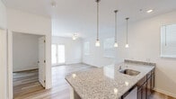 Located at 609 Grove Cir in Milton, DE, this 2-bedroom, 1-bathroom single-story home offers a clean, modern design with a bright and cohesive aesthetic throughout. The open-concept kitchen and living area serves as the heart of the home, featuring a granite-topped peninsula with an undermount sink and pendant lighting overhead. The kitchen is equipped with dark espresso cabinetry, stainless steel appliances including a refrigerator, range, and microwave, along with recessed lighting and a window that brings in natural light. The living room is airy and welcoming, with light wood-style flooring, a ceiling fan, and French doors that open to the exterior, allowing ample natural light to fill the space. Both bedrooms are comfortably sized, each with ceiling fans, large windows, and the same durable wood-style flooring. The primary bedroom includes a dedicated closet with built-in wire shelving for organized storage. The bathroom is outfitted with a granite vanity, dark wood cabinetry, a full tub-shower combination, and a grab bar, combining practicality with a polished finish. The exterior is part of a newer residential community with landscaped green space and multi-unit buildings nearby.