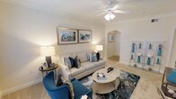 This single-story Dallas property showcases a thoughtfully designed living area that balances comfort and refined style. The living room serves as the centerpiece of the space, featuring warm neutral walls accented by crisp crown molding that frames the room with a clean, classic finish. A ceiling fan with an integrated light fixture anchors the ceiling, providing both function and a subtle decorative touch.

The flooring transitions between plush carpet in the living area and what appears to be light-toned tile beyond the arched doorway, adding visual variety and dimension. The arched passageway is a notable architectural detail, lending a soft, elegant character to the layout and connecting the living area to the adjoining spaces seamlessly.

Natural and ambient lighting work together to create a warm, inviting atmosphere throughout. The room is well-proportioned, offering comfortable seating arrangements with ample space to move. Neutral walls provide a versatile backdrop that complements the blue and cream furnishings visible in the space.

Overall, this Dallas property presents a welcoming, well-appointed interior with timeless architectural details and a cohesive, calming aesthetic.
