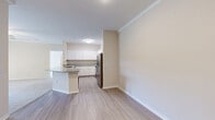 Located in Sarasota, FL, this thoughtfully designed 2-bedroom, 2-bathroom residence offers a comfortable and functional single-floor layout. The open-concept living area seamlessly connects the dining room, kitchen, and living room, creating a spacious and inviting atmosphere. Light wood-style flooring flows throughout the main living spaces, complemented by neutral warm tones and crown molding details.

The kitchen is a standout feature, boasting crisp white shaker-style cabinetry, granite countertops, a large peninsula with sink, and a full suite of stainless steel appliances including a refrigerator, range, and over-the-range microwave. This space is ideal for both everyday cooking and entertaining.

Both bedrooms are carpeted and feature ceiling fans and natural light from windows with outdoor views of the surrounding greenery. The generously sized primary bedroom includes access to a walk-in closet outfitted with wire shelving systems for organized storage. Four total closets provide ample storage throughout the unit.

The two bathrooms mirror the kitchen's design aesthetic, featuring granite-topped white vanities and wood-style flooring. The primary bathroom includes a dual-sink vanity. Additional highlights include an in-unit laundry area and a private balcony, rounding out this well-equipped Sarasota residence.