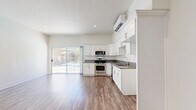 Located at 18415 Dearborn St in the Northridge neighborhood of Los Angeles, this 2-bedroom, 1-bathroom unit offers a well-designed single-floor layout. Warm wood-look flooring flows consistently throughout every room, creating a cohesive and inviting atmosphere.

The open-concept living and kitchen area is bright and airy, with high ceilings and a sliding glass door that fills the space with natural light and provides access to an outdoor patio. The kitchen is outfitted with white shaker cabinets, gray stone countertops, stainless steel appliances including a gas range, microwave, and dishwasher, and a wall-mounted mini-split unit for climate control.

The generously sized primary bedroom features its own wall-mounted mini-split system, a large window with outdoor views, and direct access to a spacious walk-in closet equipped with multi-tiered shelving rods for ample storage. The second bedroom is a comfortable, well-lit room with direct closet access.

The full bathroom is thoughtfully laid out with a sliding glass shower-tub enclosure, stone-topped vanity with white cabinetry, and consistent wood-look flooring that ties the space together. A hallway connects the rooms for a functional and efficient flow throughout the unit.