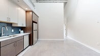 Located at 2400 Grayland Ave in Richmond, VA, this two-story loft masterfully blends industrial character with modern finishes. The main floor immediately impresses with soaring ceilings, polished concrete floors, and a dramatic painted brick accent wall. A large steel-framed window floods the open living and kitchen area with natural light and urban views. The kitchen is well-equipped with warm wood cabinetry, white subway tile backsplash, stainless steel appliances including a side-by-side refrigerator, electric range, microwave, and dishwasher, all set against a clean quartz countertop. Exposed HVAC ductwork throughout adds to the loft's industrial aesthetic. The upper floor houses the spacious primary bedroom, featuring a ceiling fan, a skylight for abundant natural light, and two generous closets offering ample storage. Two full bathrooms are finished with consistent modern detailing — white subway tile, sleek floating vanities with brushed nickel hardware, and large-format floor tile. One bathroom features a tub-shower combination, while the other offers a walk-in glass shower. Connecting the two floors are staircases that reinforce the home's open, multi-level character, making this Richmond loft a distinctive and functional urban retreat.