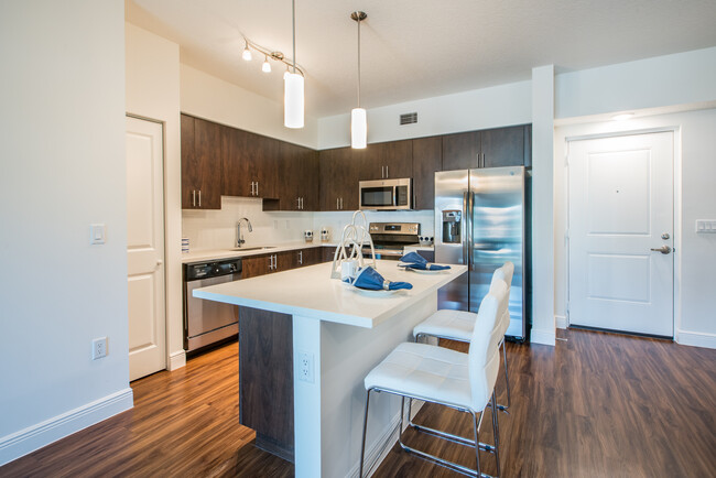 Kitchen with oak cabinetry, white countertops, white tile backsplash, and stainless steel appliances - Avalon Miramar