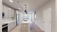 This thoughtfully designed 2-bedroom, 2-bathroom residence in Port Wentworth, Georgia offers a comfortable and modern living experience across a single floor. Light wood-look flooring flows consistently throughout, complemented by neutral warm-beige walls and crisp white trim that create a clean, cohesive aesthetic.

The kitchen serves as a centerpiece of the home, featuring shaker-style cabinetry in a soft gray-white finish, white quartz countertops, a subway tile backsplash, and a full suite of stainless steel appliances including a range, over-the-range microwave, and refrigerator. A center island with a built-in sink and pendant lighting above adds both functionality and style, while recessed lighting illuminates the open layout. A dedicated laundry room with side-by-side washer and dryer units and wire shelving provides added convenience.

Both bedrooms are well-proportioned, each equipped with ceiling fans and windows that bring in natural light and outdoor views. The spacious primary bedroom connects to a private en-suite bathroom featuring a double-sink vanity with quartz countertops, framed mirror, and a tiled walk-in shower. The second bathroom mirrors the same refined finishes. Two closets and a balcony round out this well-equipped residence.