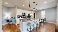 This thoughtfully designed 2-bedroom, 2-bathroom residence offers a single-floor layout that maximizes both comfort and functionality. The open-concept living area is anchored by a bright living room with large windows overlooking green outdoor views, a ceiling fan, and wide-plank hardwood-style flooring. The modern kitchen is a standout feature, boasting white shaker cabinets, granite countertops, a dark tile backsplash, stainless steel appliances, and a large center island with bar seating illuminated by stylish bronze pendant lights. The adjacent dining area benefits from abundant natural light through multiple windows. The primary bedroom is a comfortable retreat featuring plush carpet, a ceiling fan, and generous windows with outdoor views. Both bedrooms include dedicated closets with built-in shelving and hanging rods. The bathrooms are finished with granite-top vanities, white shaker cabinetry, framed mirrors, and wood-look tile accents. Two hallways connect the spaces efficiently, and the neutral gray color palette with clean white trim lends a cohesive, contemporary feel throughout the entire residence.