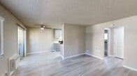 This single-story unit offers a practical, well-organized layout with a neutral color palette and updated finishes throughout. The open living area is finished with light-toned wood-look flooring, clean white baseboards, and a textured ceiling, creating a bright and cohesive atmosphere. A ceiling fan provides overhead airflow, while a wall-mounted HVAC unit and floor vents offer additional climate control. Sliding glass doors lead to an outdoor area, allowing natural light to fill the space.

The galley-style kitchen is efficiently designed, featuring gray cabinetry with contemporary hardware, white quartz-style countertops, a stainless steel sink, and stainless appliances including a range and refrigerator. A recessed overhead light panel illuminates the workspace effectively.

The bedrooms are carpeted for comfort and receive natural light through windows with blinds. Each room includes wall vents for climate control and connects to the rest of the unit via paneled interior doors.

The bathroom is cleanly finished with wood-look flooring, a tub-shower combination, and brushed nickel grab bars for added accessibility and safety. White cabinetry provides storage alongside the vanity, completing this functional and well-maintained space.