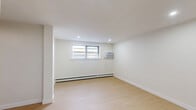 Located at 921 Tyson Ave in Philadelphia's 19111 neighborhood, this 2-bedroom, 1-bathroom unit offers a well-organized single-floor layout with a clean, modern aesthetic throughout. Light-toned hardwood flooring runs continuously across all rooms, creating a cohesive and bright interior.

The kitchen is efficiently designed with warm honey-toned cabinetry, white subway tile backsplash, light countertops, and a full suite of stainless steel appliances including a gas range, over-the-range microwave, and refrigerator. A single-basin sink with a matte black faucet completes the functional workspace.

Both bedrooms are bright and simply finished with white walls, recessed lighting, and windows fitted with baseboard heating units and wall-mounted air conditioning. The primary bedroom offers a generous footprint with multiple closets featuring white panel doors and matte black hardware, providing substantial built-in storage. The second bedroom includes a window with views to the surrounding neighborhood.

The hallway connects the main living areas and provides access to four closets distributed throughout the unit. The bathroom features a full tub-shower combination with floor-to-ceiling large-format light grey tile and matte black fixtures, offering a clean, contemporary finish. The living room completes the layout with an open, versatile space that mirrors the minimal, functional design found throughout the unit.