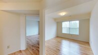 Unit 1308 at Whitehall Gardens presents a thoughtfully designed single-floor layout characterized by light hardwood flooring that flows consistently throughout the living areas and bedrooms, contributing to a cohesive and airy aesthetic. Crisp white walls complement the natural wood tones, creating a bright, neutral environment well-suited for a variety of interior styles.

The living area is generously proportioned and benefits from large windows fitted with blinds, allowing ample natural light while maintaining privacy. A sliding glass door opens directly onto a private balcony overlooking lush greenery, seamlessly connecting the interior to the outdoors.

The bedrooms are well-sized, each featuring sliding closet doors with built-in hanging rods for organized storage. Windows in each room invite natural light and views of the surrounding landscape.

The kitchen is equipped with rich, warm-toned cabinetry extending to upper and lower storage, light countertops, a double-basin sink positioned beneath a window, and includes appliances such as a gas range and dishwasher. Tile flooring grounds the kitchen space practically.

The bathroom features a wood-framed medicine cabinet mirror, a single-basin vanity with matching warm-toned cabinetry, and tile flooring, maintaining the unit's consistent design language throughout.