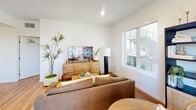 Located at 18750 Delaware St in Huntington Beach, California, this thoughtfully designed three-bedroom, two-bathroom residence offers a cohesive modern aesthetic across its single floor. Warm hardwood flooring flows throughout every room, creating a consistent and inviting foundation for the space.

The open kitchen and living area serves as the heart of the home. The kitchen is outfitted with navy-blue lower cabinetry paired with natural wood upper cabinets, stainless steel appliances including a gas range and full-size refrigerator, and a white quartz peninsula with bar seating — ideal for casual dining or entertaining. The adjacent living area benefits from natural light through large windows and connects seamlessly to a dining nook with outdoor views.

The three bedrooms are well-proportioned, with the primary bedroom offering direct access to a bathroom featuring tub-shower combination with floor-to-ceiling white tile, matte black fixtures, and a sleek navy vanity with a white countertop. Each bedroom is bright, with windows drawing in natural light. A dedicated closet provides convenient storage.

Clean white walls, recessed lighting, matte black hardware, and consistent hardwood flooring throughout give this residence a refined, contemporary character well-suited to the Southern California lifestyle.