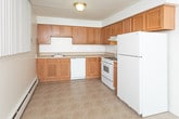 This single-floor unit at 50620 Jefferson Ave in New Baltimore, Michigan offers a straightforward, functional layout designed for comfortable everyday living. The floor plan, as illustrated by the 3D model, reveals a well-organized arrangement of living spaces that flow from one room to the next with ease.

The living area is generously proportioned, featuring neutral-toned wall-to-wall carpeting and clean white walls that create a bright, open atmosphere. Vertical blinds on the windows allow for adjustable natural light, while baseboard heating units run along the perimeter walls throughout the unit. The open sightlines connect the living space directly to the kitchen, enhancing the sense of spaciousness.

The kitchen is equipped with warm oak-toned cabinetry, ample upper and lower storage, light countertops, a white gas range with an overhead ventilation hood, and a full-size refrigerator. The flooring transitions to a resilient vinyl surface in this area.

The bedroom is a well-sized, carpeted room with a window fitted with vertical blinds and a baseboard heater, maintaining consistent design throughout. An additional carpeted room with flush-mount lighting provides flexible use as a second bedroom or living space.

The bathroom features mosaic tile flooring, a wood-toned vanity with a white countertop, a large mirror, and a combined tub and shower enclosure.
