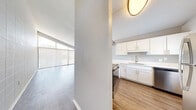 Located at 4009 N Howard Ave in Tampa, FL, this single-story home offers a clean, modern aesthetic throughout its well-appointed interior. The open-concept layout connects the living and kitchen areas seamlessly, creating a bright and functional space ideal for everyday living. The living room is a standout feature, boasting floor-to-ceiling windows with vertical blinds that invite an abundance of natural light, vaulted ceilings, and light-toned hardwood-style flooring. A decorative tile accent wall adds texture and character to the space. The kitchen is thoughtfully designed with crisp white shaker cabinetry, light countertops, a stainless steel sink, and a full suite of stainless steel appliances including a refrigerator, dishwasher, and range. A peninsula with a range hood separates the kitchen from the dining area, enhancing the open flow. The bedrooms are generously sized, each featuring hardwood-style flooring, neutral gray walls, natural window light, and wide sliding-door closets providing ample storage. The bathroom is clean and functional, featuring a tub-shower combination with tile surround, a white vanity, and coordinating brushed nickel fixtures. Consistent flooring and a neutral color palette throughout the home create a cohesive and inviting atmosphere.