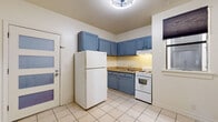 This 2-bedroom, 1-bathroom unit at 147 W Richmond Ave, Unit 305, in Richmond, CA offers a thoughtfully laid-out single-floor living space. The kitchen is a standout feature, showcasing bold blue cabinetry — both upper and lower — complemented by light tile flooring, a full-size refrigerator, electric range, and under-cabinet lighting. A glazed-panel entry door adds a modern touch to the kitchen's entryway. The living areas and bedrooms feature warm hardwood floors that flow throughout, creating a cohesive and inviting atmosphere. The primary bedroom is highlighted by a striking full-wall exposed brick accent, adding character and a loft-like aesthetic to the space. It also includes a dedicated closet with a built-in rod and shelf. The second bedroom offers natural light through a window equipped with an in-unit air conditioning unit. The full bathroom is clean and functional, featuring tile flooring, a shower/tub combo with white tile surround, a vanity, and a toilet. Two closets provide ample storage throughout the unit. The open layout connects the kitchen and living areas efficiently, making the most of the available space. Overall, the unit blends classic architectural details with practical amenities.