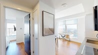Located in the heart of Calgary, this sleek one-bedroom, one-bathroom unit offers a refined urban living experience with a thoughtfully designed open layout. Warm hardwood flooring flows throughout the space, complementing the clean white walls and contemporary finishes.

The living room is a true highlight, featuring expansive floor-to-ceiling windows that frame sweeping panoramic views of the Calgary skyline and beyond. A blue leather sectional sofa anchors the space, bathed in abundant natural light. The kitchen is efficiently designed with flat-front white cabinetry, stainless steel appliances including a built-in oven and microwave, a subway-tiled backsplash, and a marble-topped dining table that seats multiple guests.

The bedroom is a calm, light-filled retreat with wall-mounted television, a closet, and access to natural light through large windows. The bathroom is finished in elegant marble-look tile from floor to ceiling, featuring a glass-enclosed walk-in shower, a floating vanity, and recessed lighting for a clean, spa-like atmosphere.

A private balcony extends the living space outdoors, offering additional access to the striking cityscape views. The unit also includes a dedicated workspace area near a window, ideal for remote work with an inspiring backdrop.