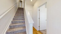 This contemporary three-story townhome at Clover in Longmont, Colorado offers a well-designed layout across three distinct floors. The ground level features an attached garage with drywall finishing and an electrical panel, providing secure and convenient parking. Carpeted staircases with clean white railings connect all three levels seamlessly.

The main living floor showcases a bright, open-concept kitchen and living area with light hardwood-style flooring throughout. The kitchen is appointed with crisp white cabinetry, granite countertops, a central island with a contrasting slate-blue base, and stainless steel appliances including a refrigerator, range, and microwave. Natural light pours in through large windows and a sliding glass door that opens to the outdoors.

The upper floor is home to three bedrooms, including a generously sized primary bedroom with a ceiling fan and a wide window offering neighborhood views. The additional bedrooms are carpeted and equally well-lit. Four bathrooms throughout the home feature granite-topped vanities with gray shaker-style cabinetry and hardwood-style tile flooring. Full bathrooms include glass-enclosed walk-in showers. Two closets and a hallway provide ample storage. The neutral palette and modern finishes give the entire home a clean, move-in-ready feel.