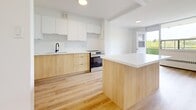 Located at 2 Park Vista in Toronto's east end, this well-appointed one-bedroom, one-bathroom unit offers a clean, modern aesthetic throughout. Light-toned hardwood flooring runs continuously across the entire space, lending a sense of warmth and cohesion.

The open-concept kitchen and living area serves as the heart of the unit. The kitchen is outfitted with two-tone cabinetry — warm wood lower cabinets paired with crisp white uppers — complemented by a white subway tile backsplash, a stainless steel appliance package including a refrigerator and range, a matte black faucet, and a central island with a white countertop that provides additional workspace and storage.

The living room benefits from floor-to-ceiling windows that flood the space with natural light and provide open outdoor views, with access to a private balcony through a glass door. Baseboard heating units are positioned beneath the windows throughout the unit.

The spacious bedroom features its own window with natural light and direct access to a dedicated closet, with a second closet also available in the unit for additional storage.

The bathroom is finished with large-format white tiles, a soaking tub with chrome hardware, and a wood-toned vanity with a white countertop. The overall palette of the unit is bright, neutral, and move-in ready.
