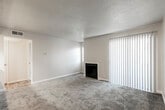 This single-floor residential unit offers a thoughtfully designed open-concept layout that seamlessly connects the main living and kitchen areas. The living room is finished with plush carpeting and features a fireplace, a ceiling fan with lighting, and sliding glass door access to a private outdoor area, allowing natural light to fill the space.

The kitchen is designed with functionality in mind, featuring a pass-through breakfast bar that opens to the living area. White cabinetry provides ample storage, while dark countertops offer a contrasting aesthetic. The kitchen is equipped with black appliances, including a refrigerator, electric range, over-the-range microwave, and dishwasher, all set atop wood-style vinyl flooring that extends through the kitchen and entry areas.

The bedroom is a well-proportioned, carpeted room with a window overlooking a tree-lined exterior, providing a calm, naturally lit atmosphere. The bathroom is finished with a wide vanity topped with dark countertops and white cabinetry, complemented by a large mirror, modern light fixtures, and wood-style flooring. A window above the vanity introduces additional natural light. The unit also includes dedicated HVAC vents throughout, ensuring consistent climate control across the entire floor plan.