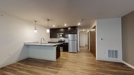 Located at 350 Maloney Dr in Fitchburg, Wisconsin, this single-floor unit offers a thoughtfully designed layout with modern finishes throughout. The open-concept kitchen serves as the heart of the space, showcasing dark espresso cabinetry, granite countertops, a large peninsula with an integrated sink, and stainless steel appliances including a refrigerator, electric range, microwave, and dishwasher. Stylish pendant lighting hangs above the peninsula, adding a contemporary touch, while recessed lighting provides consistent illumination throughout. Durable hardwood-style flooring extends through the kitchen and living areas, creating a cohesive and easy-to-maintain aesthetic. The spacious living area features neutral-toned walls and ample room for furnishings, with windows that invite natural light. A hallway leads to additional rooms, including a bedroom with two windows and wood-style flooring, offering a bright and comfortable retreat. The bathroom is well-appointed with dark vanity cabinetry, a granite-top sink, a full tub-shower combination with a curved curtain rod, and clean tile flooring. The overall design balances practicality with modern style, making this a well-equipped and inviting space.
