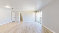 This 2-bedroom, 3-bathroom single-floor residence features a clean, modern aesthetic with a neutral color palette throughout. The combined living and dining area is a bright, open space anchored by light-toned wood-look flooring that runs throughout the main living areas. Large sliding glass doors provide direct access to an outdoor balcony, allowing natural light to fill the room. The kitchen is well-equipped with gray shaker-style cabinetry, white countertops, and stainless steel appliances including a full-size refrigerator, range, and dishwasher. A hallway connects the living spaces to the private sleeping quarters. The primary bedroom is generously sized, featuring plush carpeting, a dedicated walk-in closet with built-in shelving, and a private en-suite bathroom. The en-suite is finished with a gray vanity, white countertop, a large mirror with modern lighting, and a shower. The second bedroom also features wood-look flooring and a closet. Three full bathrooms provide ample convenience for residents and guests. With four closets total distributed throughout the home, storage is a practical highlight. The overall design is cohesive, clean, and move-in ready.