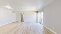 This 2-bedroom, 3-bathroom single-floor residence features a clean, modern aesthetic with a neutral color palette throughout. The combined living and dining area is a bright, open space anchored by light-toned wood-look flooring that runs throughout the main living areas. Large sliding glass doors provide direct access to an outdoor balcony, allowing natural light to fill the room. The kitchen is well-equipped with gray shaker-style cabinetry, white countertops, and stainless steel appliances including a full-size refrigerator, range, and dishwasher. A hallway connects the living spaces to the private sleeping quarters. The primary bedroom is generously sized, featuring plush carpeting, a dedicated walk-in closet with built-in shelving, and a private en-suite bathroom. The en-suite is finished with a gray vanity, white countertop, a large mirror with modern lighting, and a shower. The second bedroom also features wood-look flooring and a closet. Three full bathrooms provide ample convenience for residents and guests. With four closets total distributed throughout the home, storage is a practical highlight. The overall design is cohesive, clean, and move-in ready.