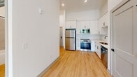 Located at 223 Long Shoals Rd in Asheville, NC, this thoughtfully designed one-bedroom, one-bathroom unit offers a clean, modern aesthetic across its single-floor layout. Light hardwood flooring runs throughout the space, complementing the bright white walls and creating a cohesive, contemporary feel.

The kitchen is a standout feature, equipped with white shaker-style cabinetry, a classic subway tile backsplash, stainless steel appliances including a refrigerator, range, built-in microwave, and dishwasher, as well as a single-basin sink with a matte black faucet. The kitchen's efficient design maximizes both storage and functionality.

The bedroom benefits from soaring ceilings that lend an open, airy quality to the space, along with a large window that invites natural light and provides views of the surrounding greenery. The room also provides direct access to a dedicated closet with built-in shelving and hanging rods, offering practical storage solutions.

The bathroom features a full tub-shower combination with large-format neutral tile surround and matte black fixtures, maintaining the unit's consistent modern design language. The overall ambiance of this unit is clean, bright, and move-in ready, making it a well-appointed option in the Asheville area.