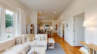 This single-floor residence combines contemporary design with a bright, airy atmosphere throughout. The entry hallway sets an elegant tone, featuring warm hardwood flooring, crisp white walls, and curated artwork that leads the eye toward the main living areas.

The open-concept living and dining space is filled with natural light, courtesy of expansive floor-to-ceiling windows and a glass door that opens to a private balcony overlooking lush greenery. The living area offers generous proportions, recessed lighting, and a seamless connection to the kitchen and dining zone.

The kitchen is well-equipped with gray shaker-style cabinetry extending to the ceiling, stainless steel appliances including a refrigerator, range, microwave, and dishwasher, along with a white tile backsplash and a butcher-block topped island that doubles as a casual dining surface.

The bedrooms are tranquil retreats, each benefiting from large windows that invite natural light and outdoor views. Hardwood floors continue throughout, adding warmth and continuity.

The bathroom is clean and minimal, featuring a glass-enclosed walk-in shower with white tile surround and polished chrome fixtures. Overall, the space presents a cohesive, modern aesthetic with thoughtful design details.