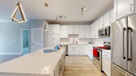 This single-floor residence showcases a thoughtfully designed open layout with consistent, contemporary finishes throughout. The kitchen serves as a central highlight, featuring white shaker-style cabinetry extending to the ceiling, a classic subway tile backsplash, and light quartz countertops. A spacious island with a waterfall edge provides additional prep space and seating, while a geometric pendant light adds a modern design touch. The full suite of stainless steel appliances includes a French door refrigerator, electric range, over-the-range microwave, and dishwasher. Light wood-tone luxury vinyl plank flooring runs through the main living and kitchen areas, creating a clean, cohesive aesthetic.

The living area offers natural light through multiple windows and features a ceiling fan overhead, with direct access to an exterior door. Bedrooms are carpeted and include ceiling fans; at least one bedroom features a walk-in closet with built-in shelving. The bathrooms are finished with warm wood-tone LVP flooring, white vanity cabinetry, quartz countertops, framed mirrors, and clean-lined fixtures. One bathroom includes a glass-enclosed shower, while another offers an open, accessible layout.