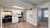 Located at 1605 Buchanan St NW in Atlanta, GA, this single-floor residence offers a thoughtfully updated interior with a clean, contemporary design. The kitchen serves as a standout feature, outfitted with crisp white shaker-style cabinetry, granite-look countertops, a subway tile backsplash, and a full suite of stainless steel appliances including a refrigerator, electric range, and dishwasher. A stacked washer and dryer unit is conveniently integrated within the kitchen area. Durable wood-look plank flooring runs throughout the main living and kitchen areas, providing a warm yet low-maintenance surface. The neutral gray wall tones create a cohesive, modern palette across the space. Bedrooms offer a mix of flooring options — one features plush wall-to-wall carpeting, while another showcases the same wood-look planks, each room receiving natural light through blinded windows. The bathroom includes a full tub-shower combination with classic white tile surround, maintaining a clean and functional design. Overhead lighting throughout the unit ensures well-lit interiors. The overall layout is efficient and open, making it a practical and move-in-ready space in the heart of Atlanta.