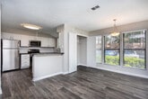 Located at 2703 Delk Rd SE in Marietta, Georgia, this single-floor residence offers a thoughtfully designed open-concept layout. The expansive living and dining areas are finished with rich wood-look flooring and neutral-toned walls, creating a warm and inviting atmosphere. Multiple large windows fitted with horizontal blinds allow abundant natural light to fill the space, while providing views of the surrounding greenery. A textured ceiling adds character throughout the common areas.

The kitchen is a functional highlight, featuring crisp white shaker-style cabinetry, dark countertops, and a classic white subway tile backsplash. Stainless steel appliances — including a gas range, over-the-range microwave, and dishwasher — complete the modern look, along with a stainless sink positioned beneath a bright window.

The bedrooms are carpeted for comfort, with neutral walls and ceiling fans providing a relaxed retreat. One bedroom includes a spacious walk-in closet with built-in shelving, offering generous storage. The bathroom is well-appointed with a tiled tub-and-shower combination, brushed nickel fixtures, and wood-look flooring that ties into the rest of the home's design. The overall layout is efficient and connected, making this Marietta home ideal for comfortable everyday living.