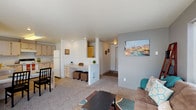 Located at 12517 E Broadway Ave in Spokane Valley, WA, this single-floor unit offers a practical and well-organized layout suited for comfortable residential living. The open-concept living area is finished with plush carpeting and neutral-toned walls, creating a welcoming atmosphere. A built-in desk nook with a half-wall partition separates the living space from the kitchen, adding functional versatility to the layout. The living room features ample natural light through large windows and provides access to an outdoor area via sliding glass doors.

The kitchen is well-appointed with light wood cabinetry, generous counter space, wood-look flooring, and a full suite of white appliances including a refrigerator, electric range, and dishwasher. A window above the sink brings in additional natural light.

The unit includes multiple carpeted bedrooms, each offering a comfortable and quiet retreat. One bedroom features a window with views of surrounding greenery, while another provides a spacious layout suitable as a study or guest room. The full bathroom includes a vanity with storage cabinetry, a combination tub and shower, and wood-look tile flooring. Throughout the unit, the design emphasizes clean lines and functional simplicity.