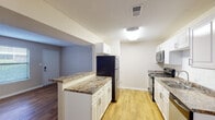 This single-story, 2-bedroom, 1-bathroom residence in Gulf Breeze, Florida offers a well-organized layout with consistent wood-look flooring throughout. The open living area is bright and welcoming, featuring a textured ceiling, neutral warm-toned walls, and a ceiling fan. A half-wall peninsula with granite-style countertops connects the living space to the kitchen, providing both visual openness and functional separation. The galley-style kitchen is efficiently designed with white cabinetry, granite-style countertops, a subway tile backsplash, and stainless steel appliances including a refrigerator, electric range, microwave, and dishwasher. Both bedrooms feature ceiling fans, wood-look flooring, natural light from windows with blinds, and access to closet storage — one bedroom includes a walk-in closet. The full bathroom is finished with a white vanity, granite-style countertop, a large mirror with overhead lighting, and a shower-tub combination. The unit is completed by a front entryway with a window that allows additional natural light into the space. Clean, neutral finishes throughout create a cohesive and functional living environment well-suited to the Gulf Breeze area.
